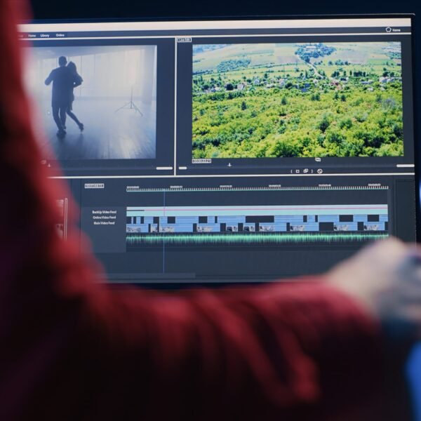 Professional video editor editing color grading and lighting in creative office, analyzing film montage, close up shot. Post production videographer manipulates raw footage, handheld camera shot