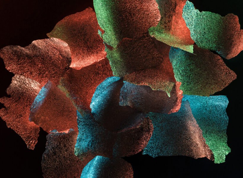 abstract background of textured foil pieces with colorful illumination isolated on black